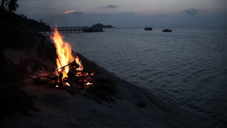 camp fire on a hill of island with overview of sea during magic hour