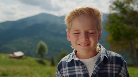 portrait happy boy looking camera on mountains. little man standing on meadow.