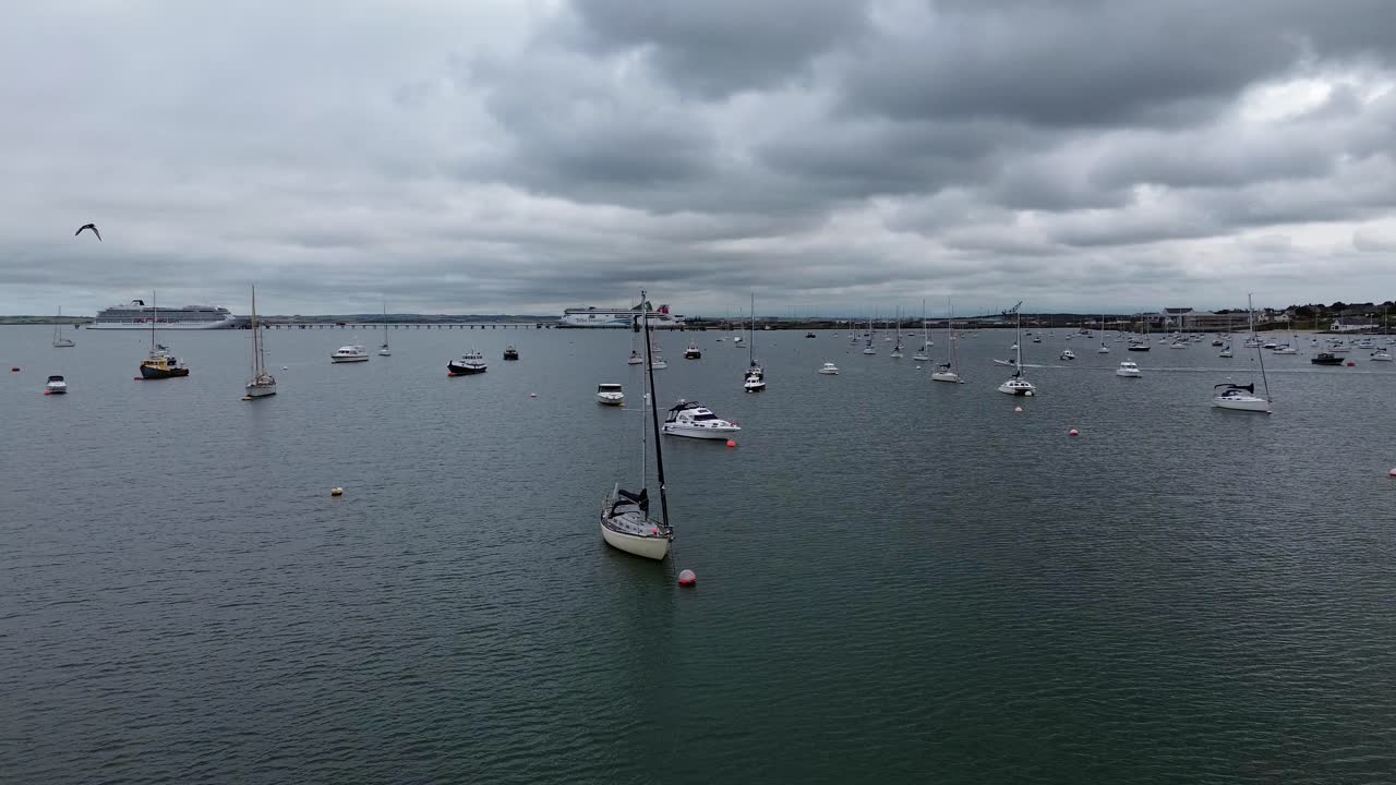 Flying across Holyhead breakwater marina passing yachts and boats floating in the town bay
