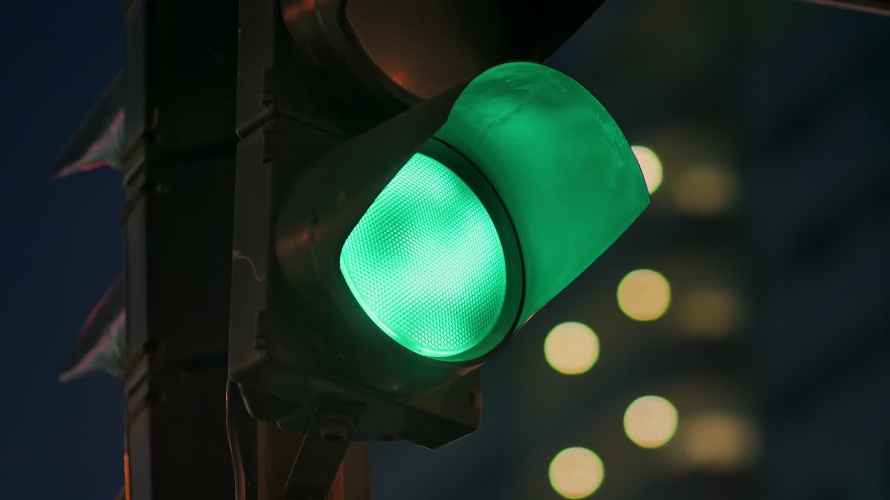 Traffic light against the background of the evening city flashes green and changes to orange