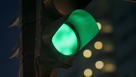 traffic light against the background of the evening city flashes green and changes to orange