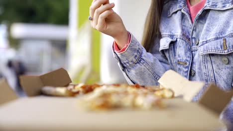 woman eating pizza outdoors