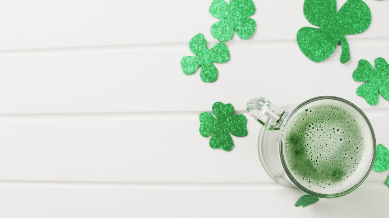Video of st patrick's green shamrock and green beer with copy space on white background