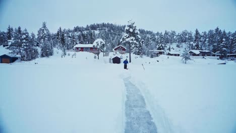 man sled shoveling mass of snow in winter foreground making a pathway at rural area near trondheim, norway