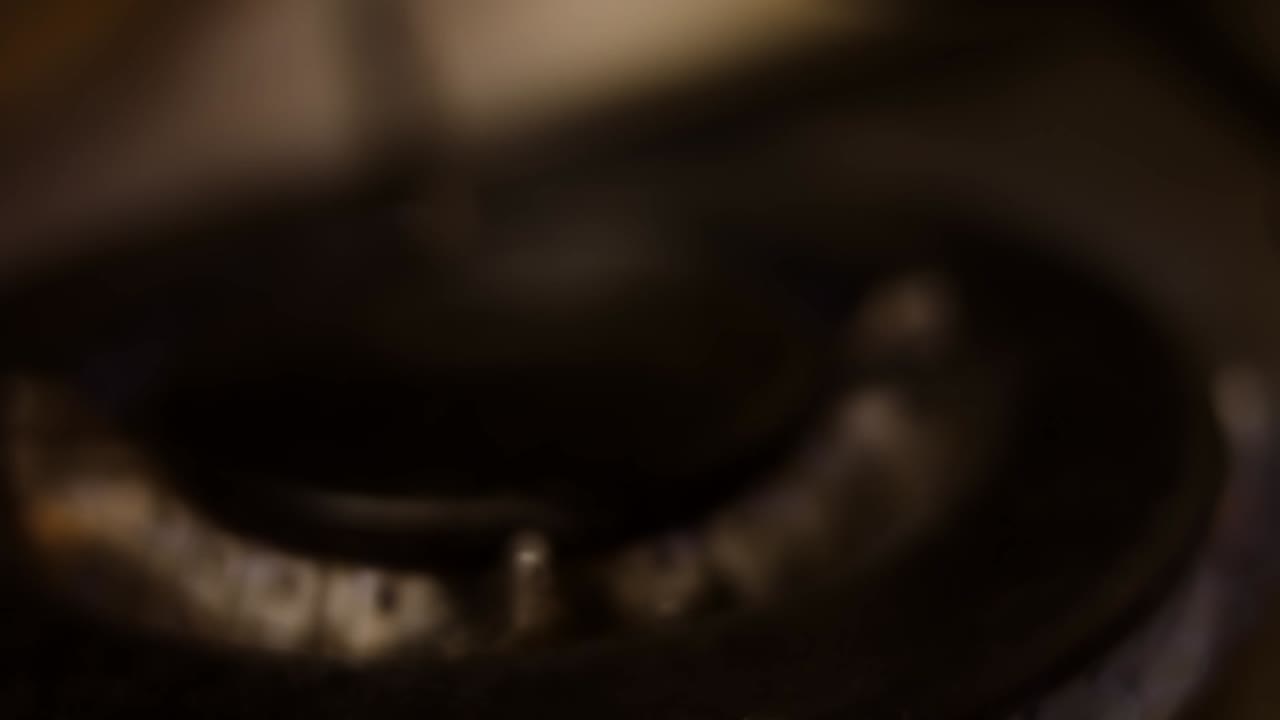 Turning on the cooktop gas cooker on black background. Kitchen burner turning on. Close up on the flame. Natural gas inflammation in stove burner, close up view. Gas burning from a kitchen gas stove