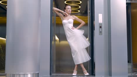 mujer con vestido blanco posando en el ascensor