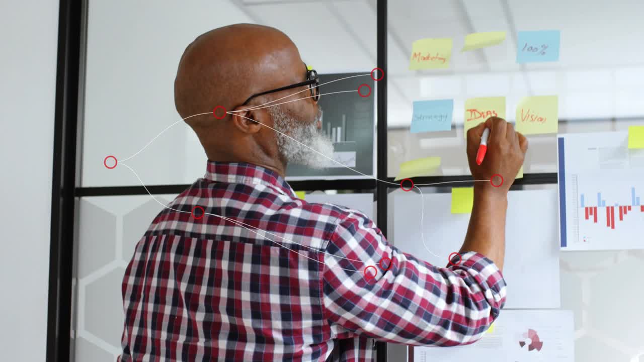 Man shifting and attaching charts on glass panel, planning business strategy with sticky notes