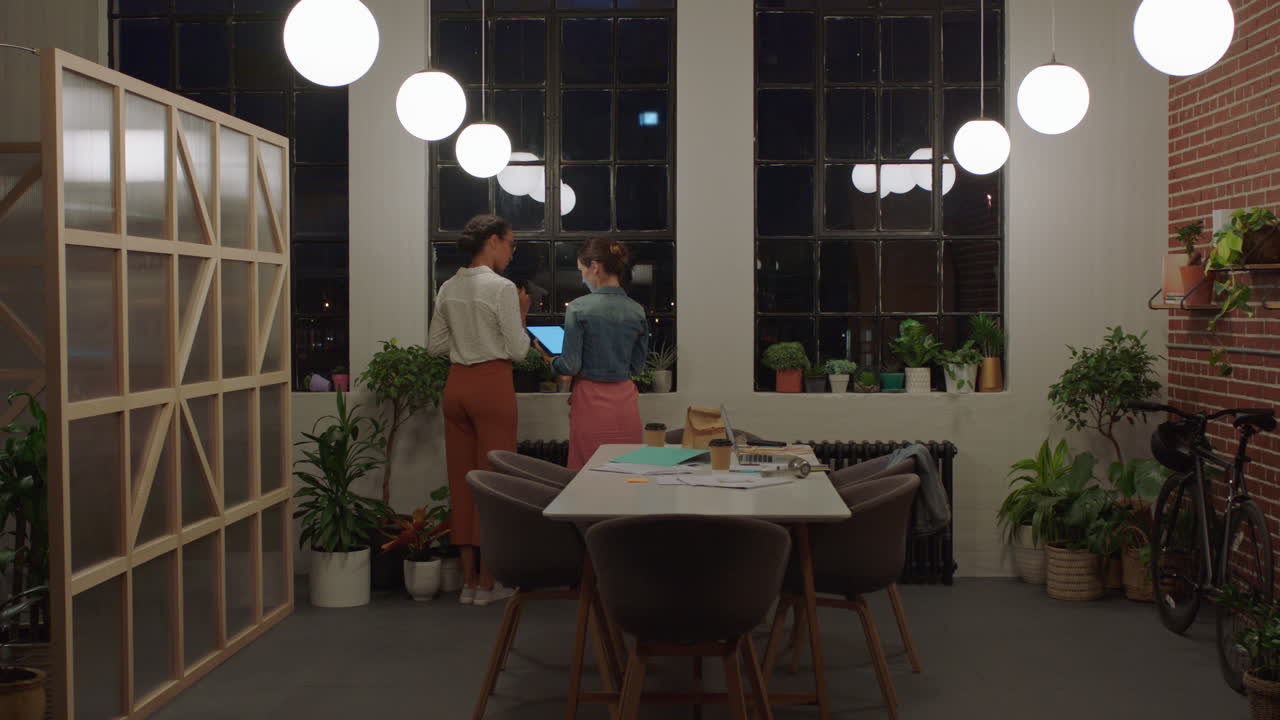 늦게 일하는 사업가 동료들이 아이디어를 모으고 태블릿 컴퓨터를 사용하여 마감일을 계획하고 협업하고 저녁에 사무실에서 약속을 공유합니다.