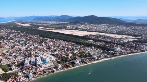 drone aéreo escena alta playa florianópolis vista desde lo alto pueblo costero cerca del mar con montañas dunas horizonte edificios fraccionamiento urbano en la costa playa inglesa edificios frente al mar