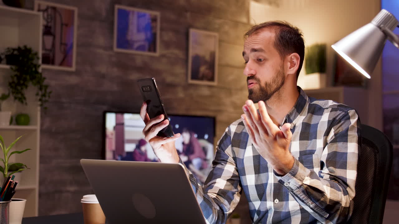 Uomo che lavora da casa in videochiamata con laptop e smartphone
