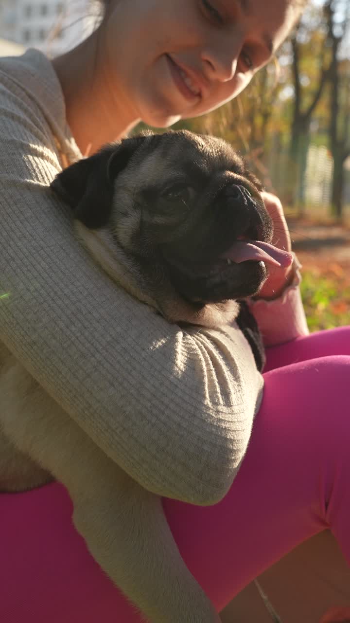 una chica acurrucando a un cachorro en un parque.