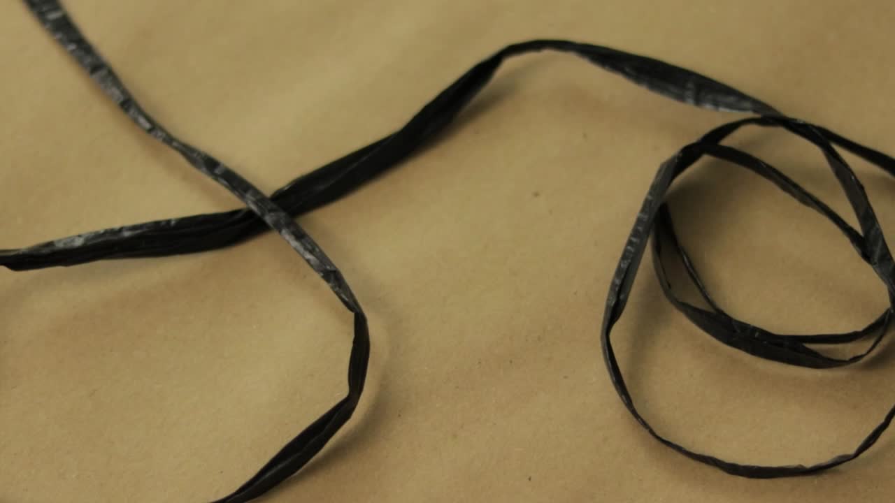 Thin strip of black raffia delicately arranged on textured craft paper