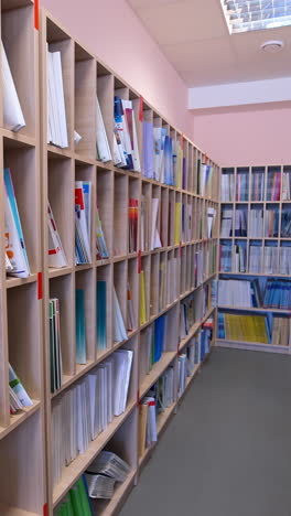 modern bookstore. educational literature stacked on shelves for students in the library. wooden bookcases with many books indoors. vertical video
