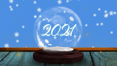 Animation-of-2021-in-snow-globe-on-wooden-boards,-shooting-star-and-snow-falling