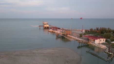 slow-motion aerial view of fishing huts on shores of estuary at sunset,italian fishing machine, called ""trabucco"",lido di dante, ravenna near comacchio valley