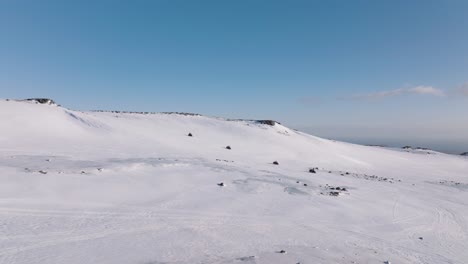 Luftaufnahme-Einer-Landschaft-Mit-Menschen,-Die-An-Einem-Sonnigen-Abend-Auf-Dem-Eisigen-Boden-Eines-Gletschers-In-Island-Mit-Schneemobilen-Unterwegs-Sind