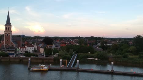 boat docked at pier near coastal town with church tower, aerial view