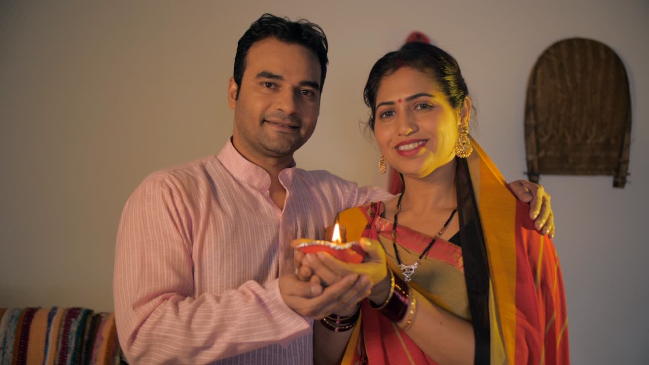 Village scene of an Indian married couple happily holding a burning clay lamp