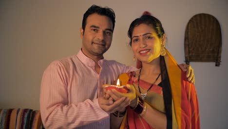 village scene of an indian married couple happily holding a burning clay lamp
