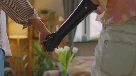 woman with prosthetic arm holding hands with friend