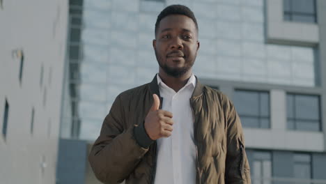 man giving thumbs up in front of modern building