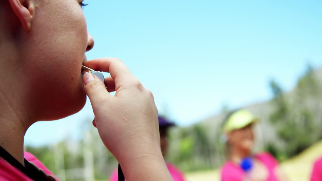 entrenadora mirando el cronómetro mientras sopla el silbato