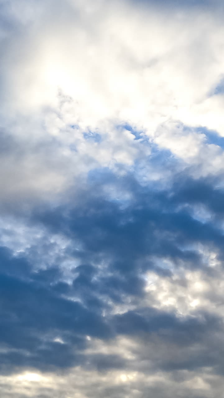Movement of fluffy clouds along the horizon. Spindrift cloudscape covering the skies and shielding the sun. Timelapse. Vertical video