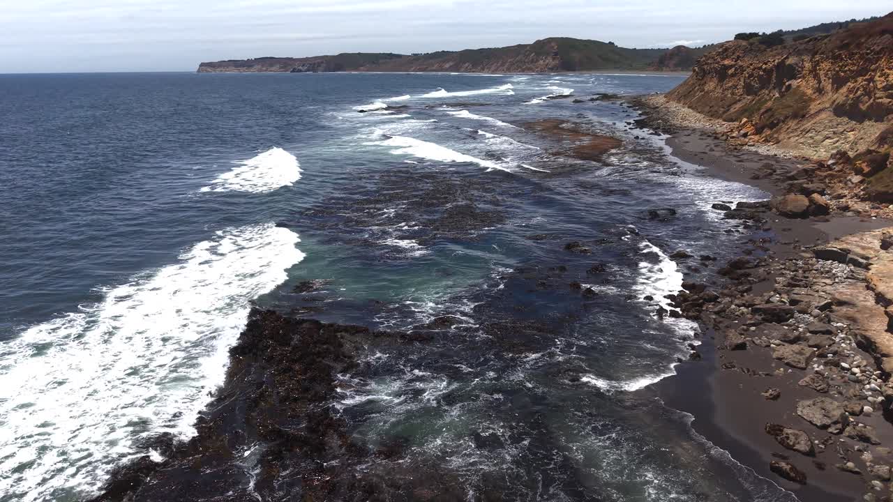 Ripresa aerea cinematografica con drone lungo ripide scogliere costiere e onde oceaniche che si infrangono sotto un cielo nuvoloso in Cile, 4K