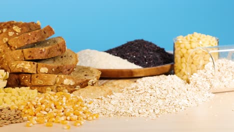 A variety of grains and breads displayed on a table with a bright blue backdrop, highlighting textures and colors