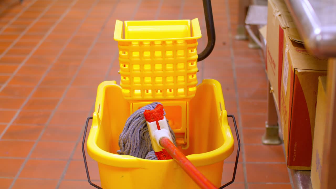 Industrial yellow mop and bucket on a floor with a stable video shot.