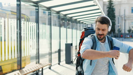 cheerful young caucasian traveller in headphones walking down the street and dancing