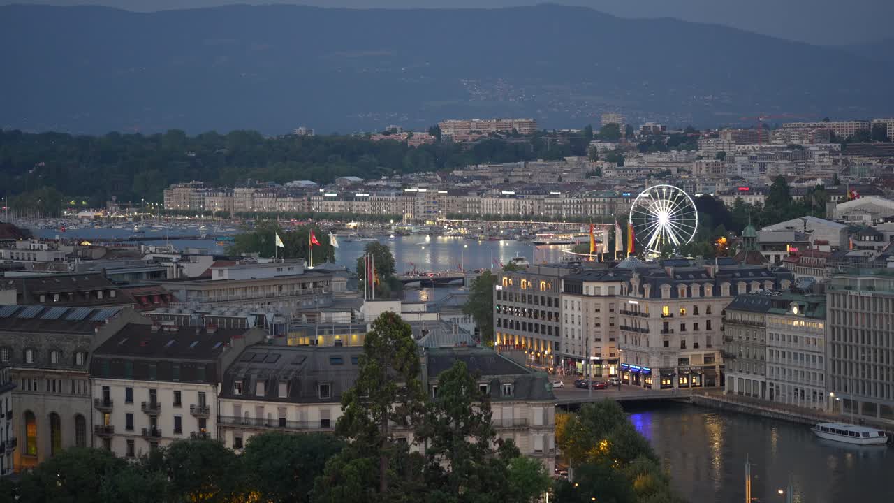 Day to night timelapse of Geneva waterfront with famous Jet dEau turning on and city lights illuminating buildings ferris wheel lake boats and reflections in the evening atmosphere