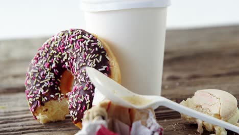 Waste-tissue-paper,-coffee-cup-and-half-eaten-chocolate-doughnut-with-sprinkles