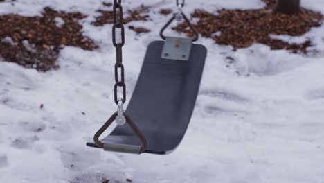 swing in a park in winter sways back and forth in the wind of the january or february day