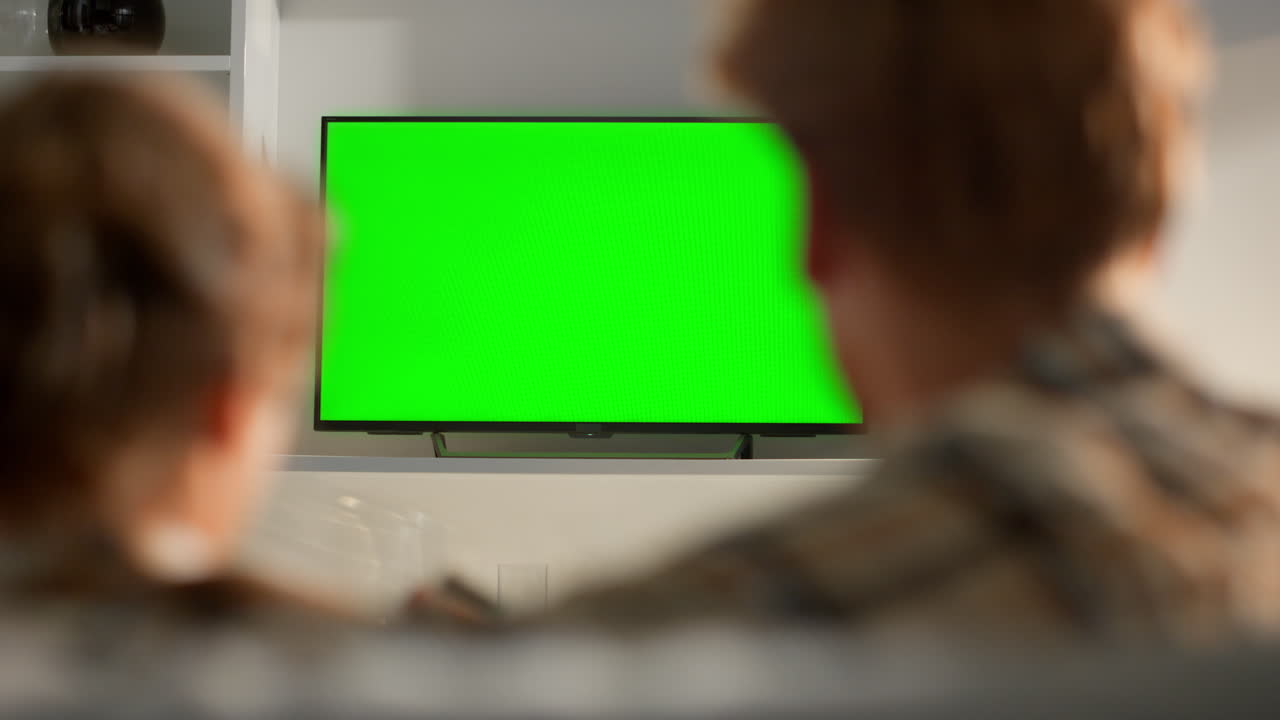 Wife zapping green tv screen switching channels. Family routine watching shows