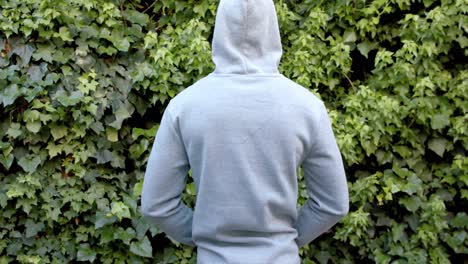 Rear-view-of-african-american-man-in-grey-hooded-sweatshirt-top-in-garden,-copy-space,-slow-motion