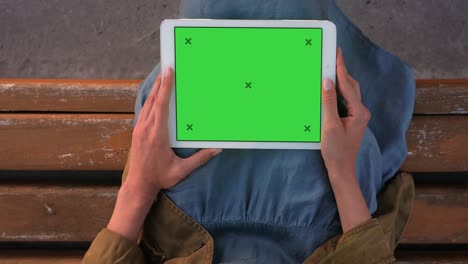 lady holding tablet while sitting on a bench