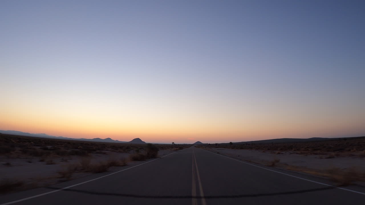 그림 같은 일몰 동안 외로운 길에서 모하비 사막을 통해 운전 - 관점