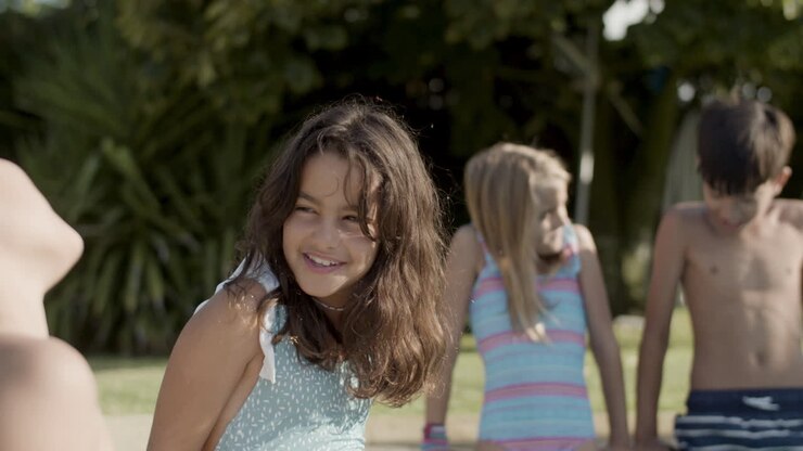 Niños sentados al borde de la piscina hablando, relajándose al aire libre