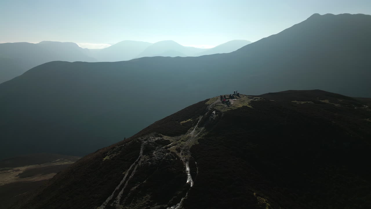 excursionistas en la cumbre de la montaña con revelación panorámica de misty mountains en english lake district reino unido