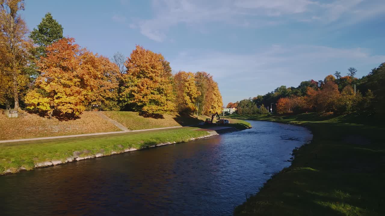 Colourful golden autumn trees line River Ostravice in Komenský Park
