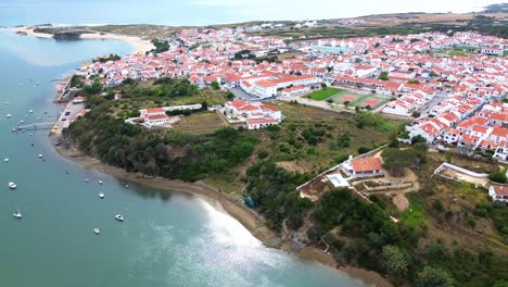 aerial-view-over-small-coastal-town,-blue-ocean,-red-roofs,-4k