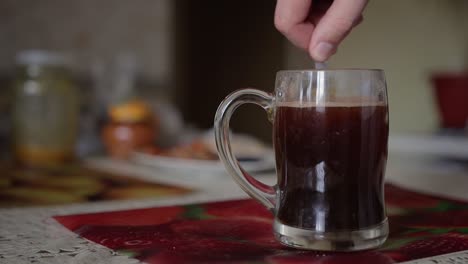 man stirs black coffee with honey
