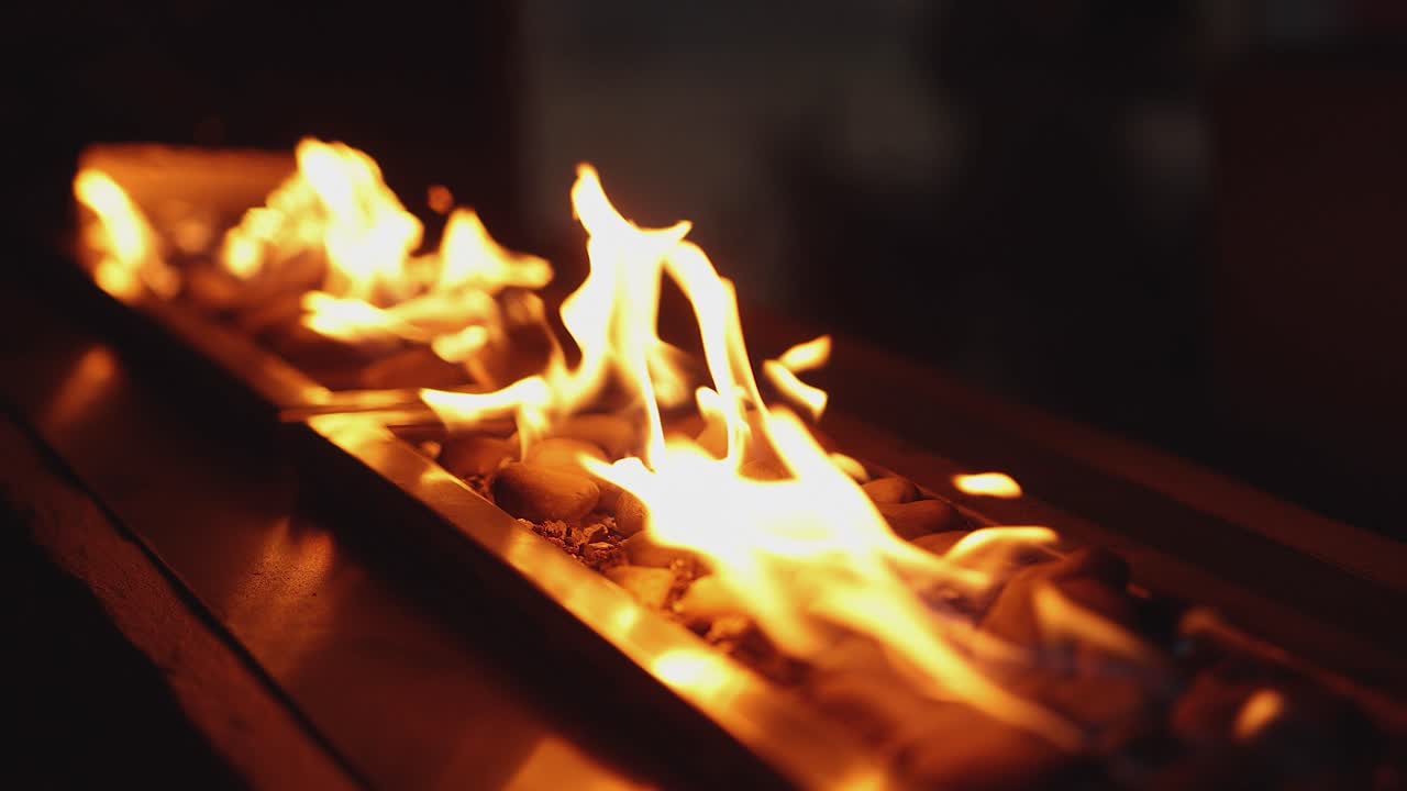 Gold indoor fire pit decor: Gas flames burn in artistic stone fireplace