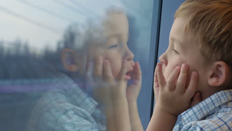 niño mirando por la ventana del tren con las manos en la cara