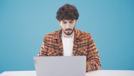 Young-man-using-laptop-at-table-typing-on-keyboard-serious-and-focused.