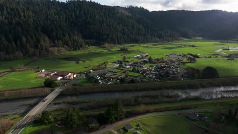 Drone-shot-of-Orick,-California-on-a-sunny-day-with-green-fields-and-some-clouds