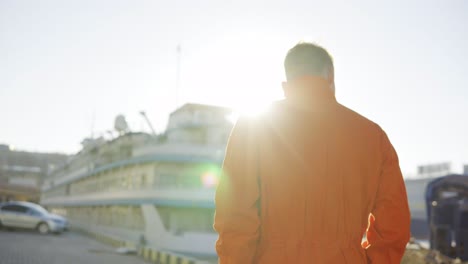 Hafenarbeiter-In-Orangefarbener-Uniform,-Der-Im-Hafen-Spaziert-Und-Den-Arbeitsprozess-Im-Hafen-Kontrolliert