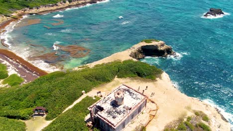 tourists strolling by puerto ferro lighthouse in vieques, puerto rico - orbit drone shot