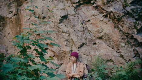 worried woman standing near rock in forest